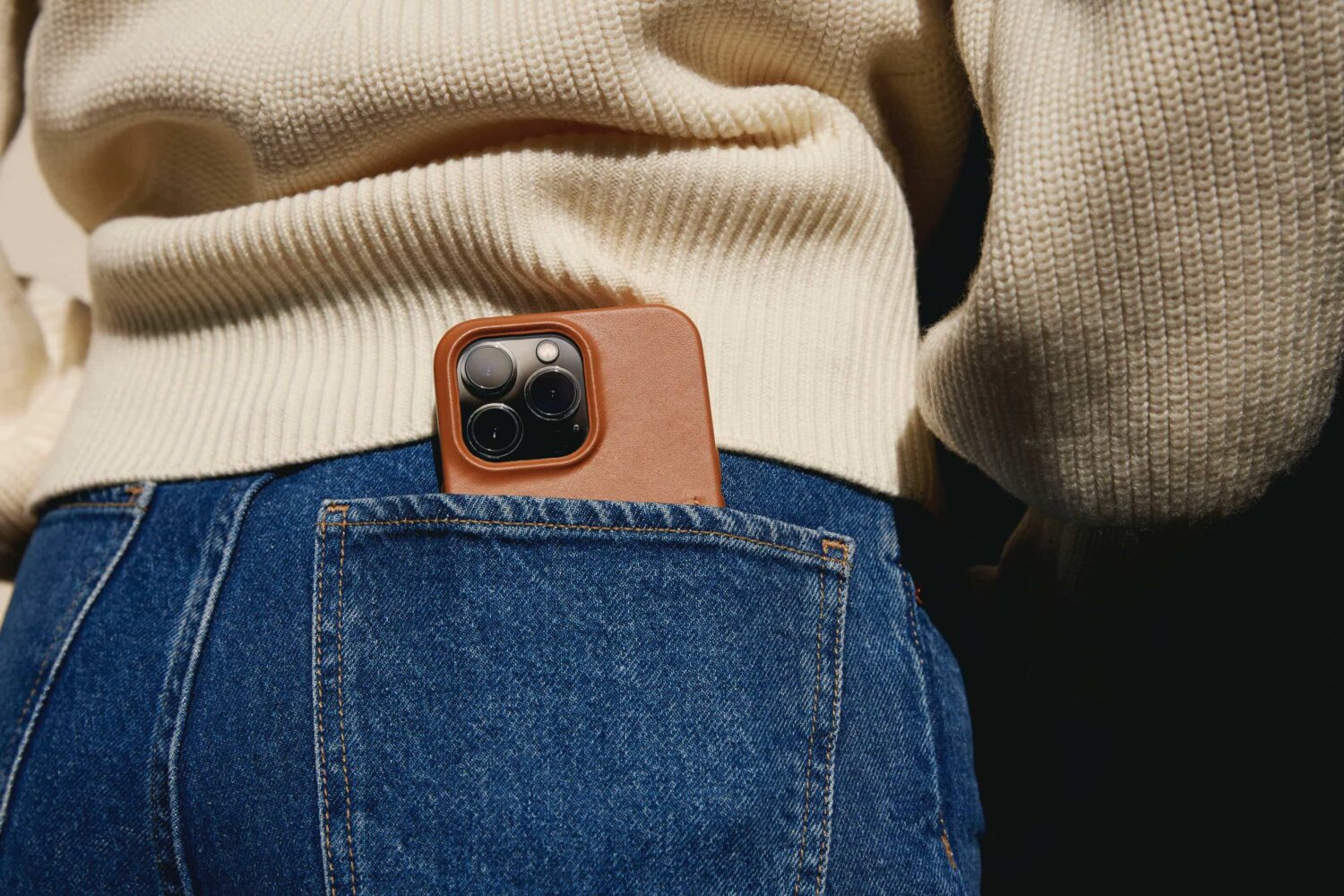 iPhone 14 in Mujjo's leather wallet case slipped into a woman's back jeans pocket