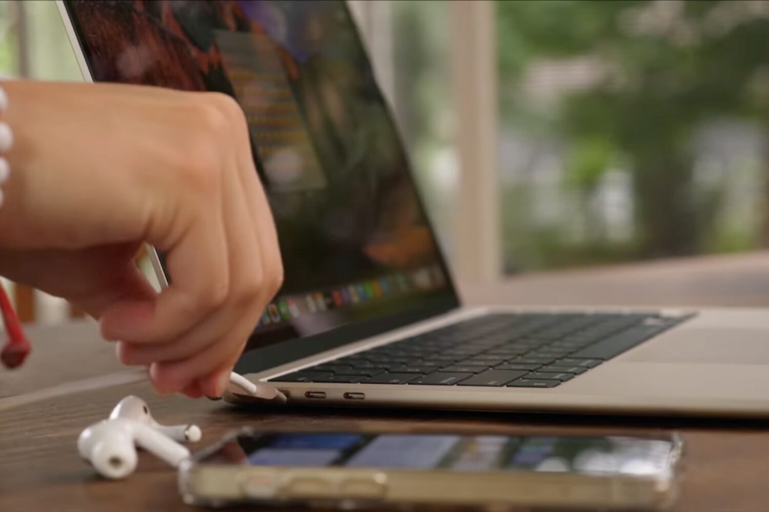 Male hand plugging a cable into the MacBook Air's MagSafe power port