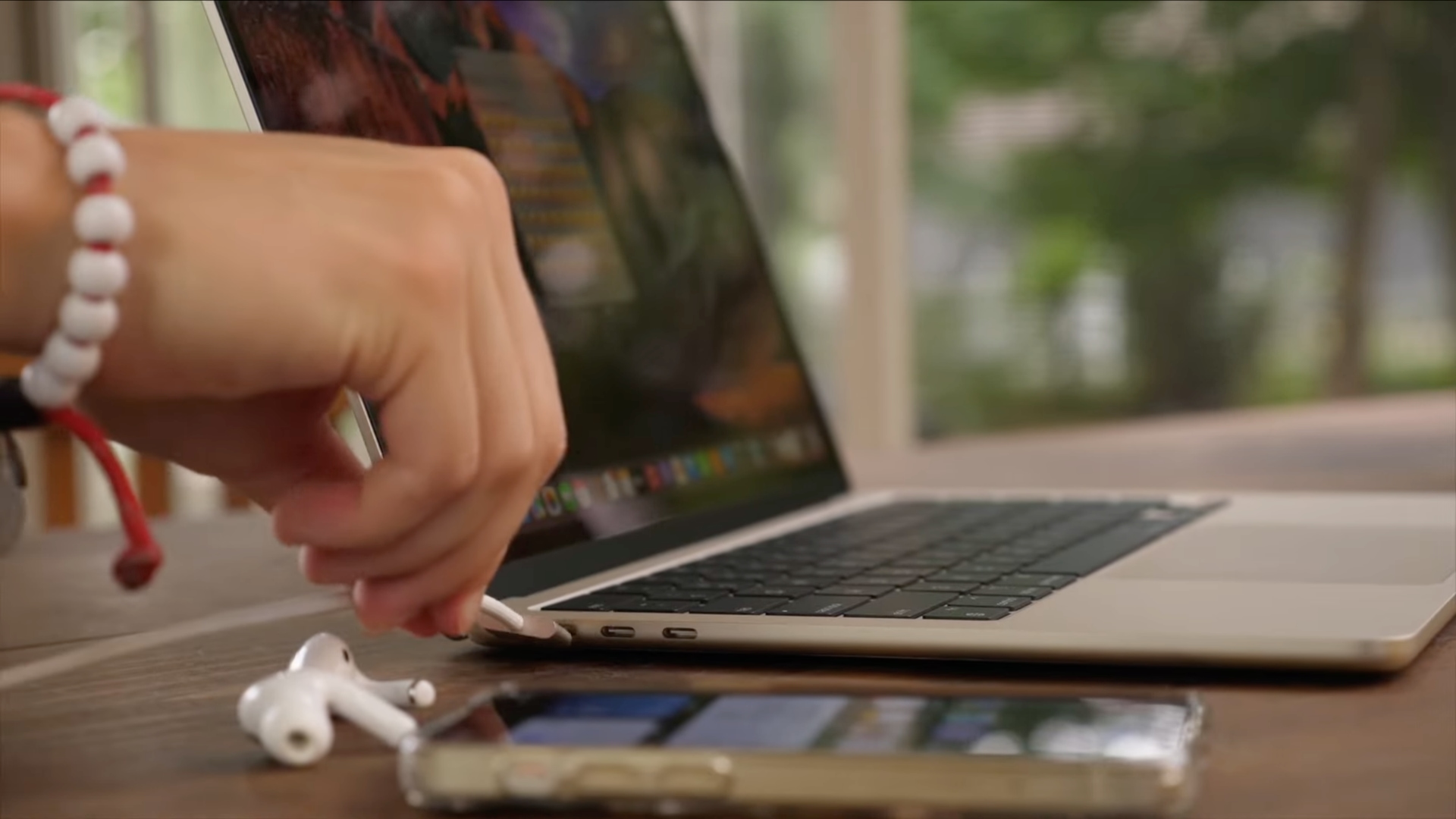 Male hand plugging a cable into the MacBook Air's MagSafe power port