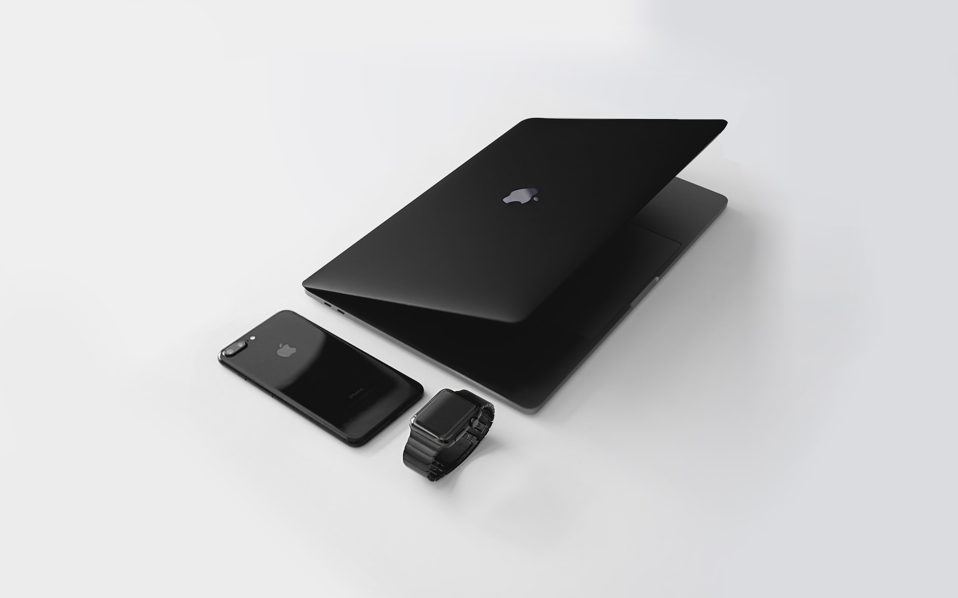 iPhone hitam, MacBook, dan Apple Watch disimpan bersama