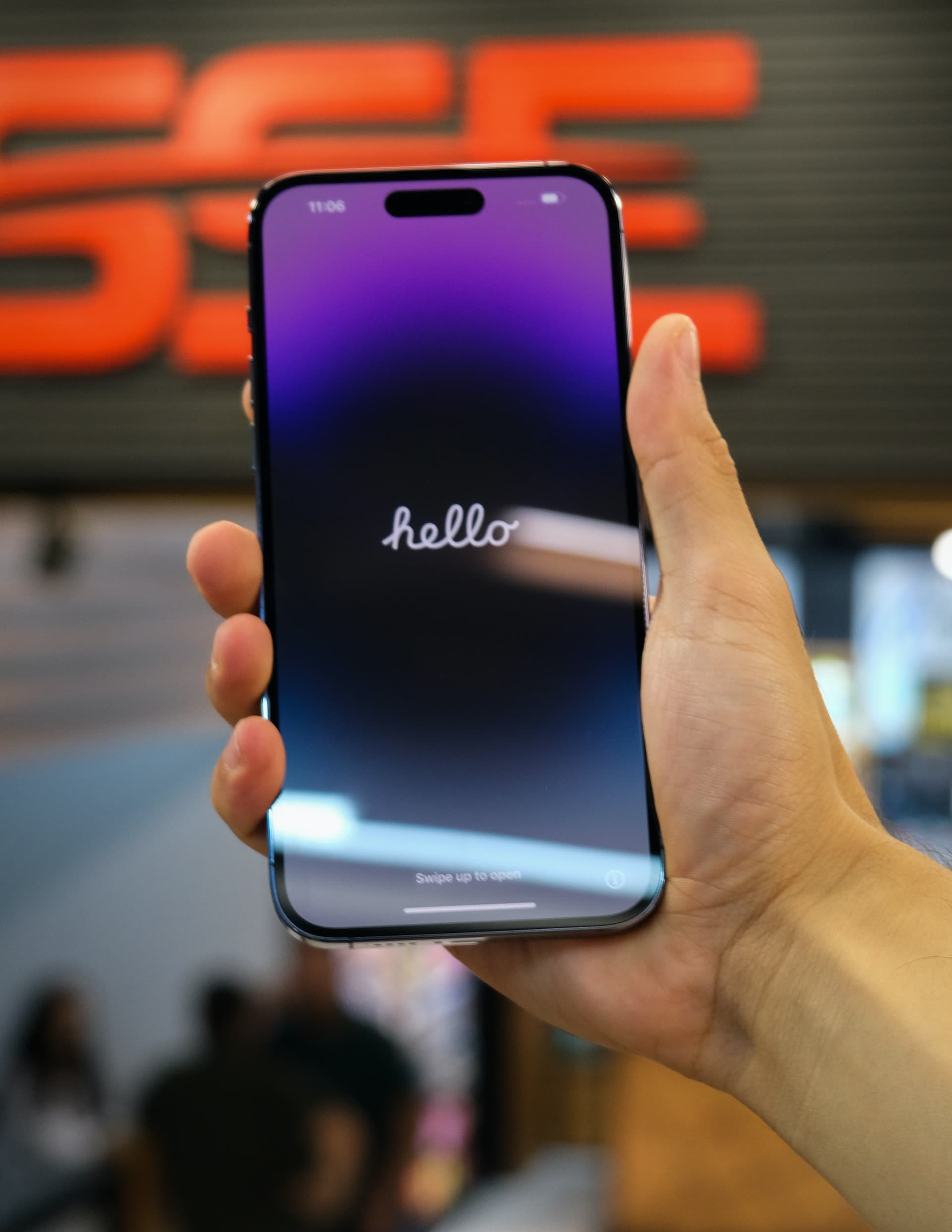 A person holding an iPhone 14 Pro, which is on its setup screen and showing the word hello