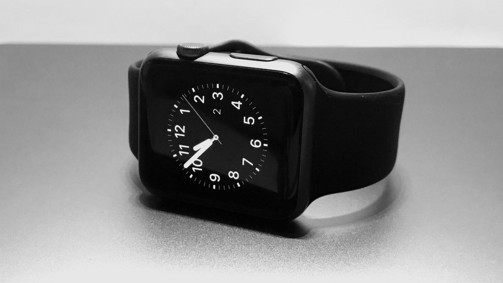 Black Apple Watch with black sports band, sitting on its side