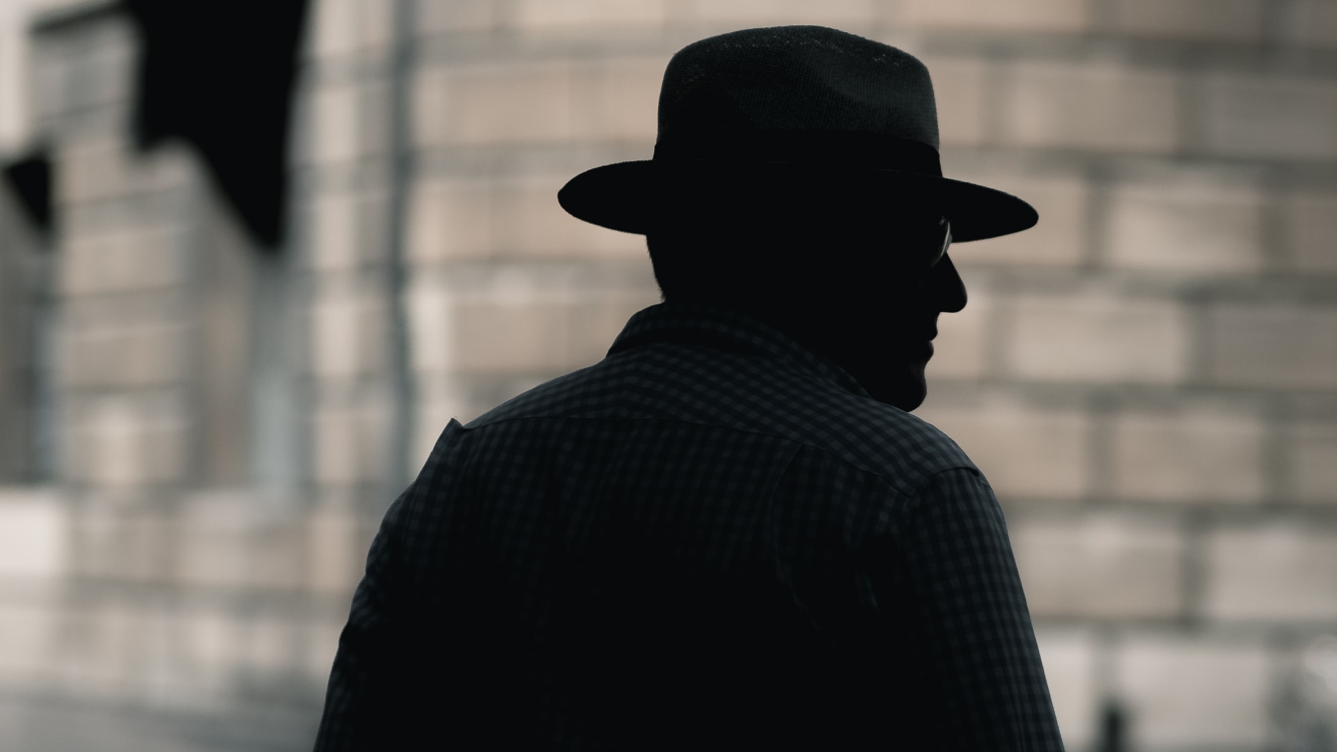 Silhouette of a detective standing on the street, set against a blurred focus background