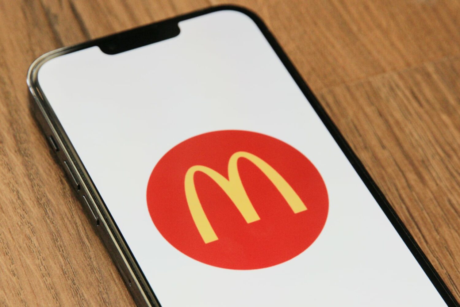 iPhone resting on a wooden table, showing the McDonald's logo
