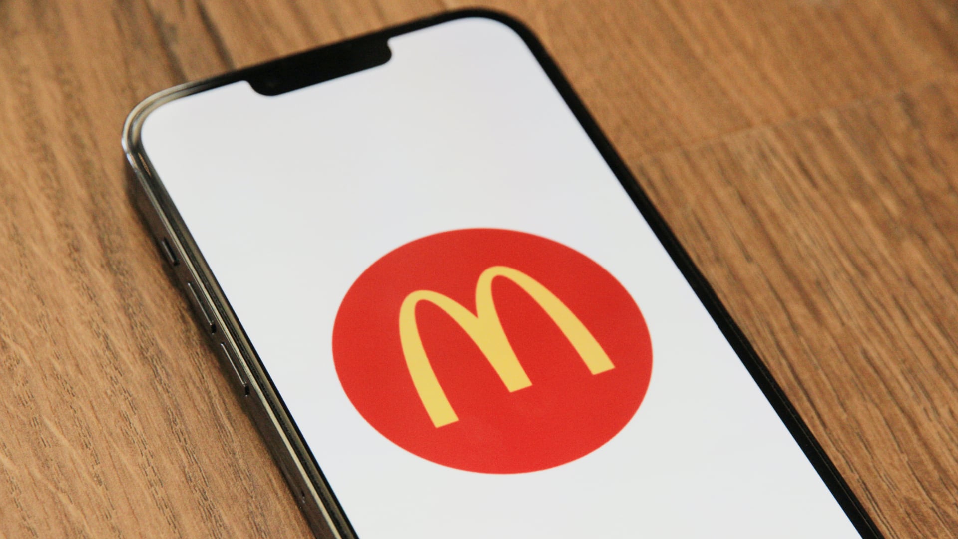 iPhone resting on a wooden table, showing the McDonald's logo