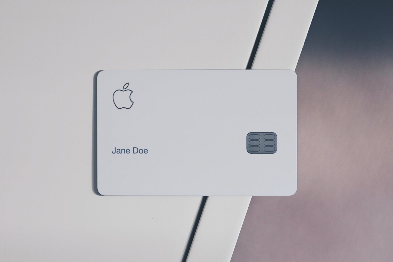 Apple Card with the Jane Doe name near the edge of a white desk