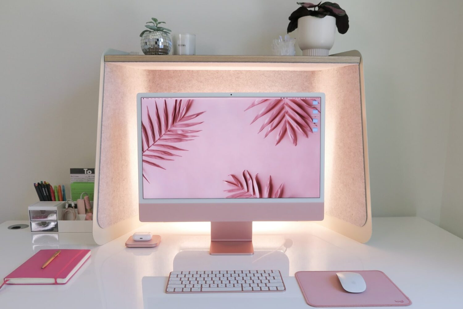 Pink 24-inch iMac on a desk with back lighting