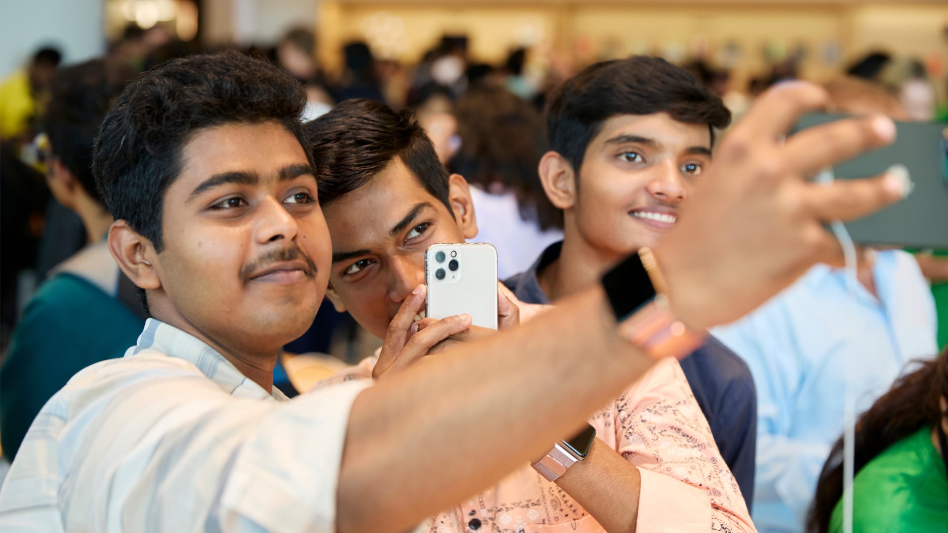 Closeup of there young man taking a selfie with an iPhone at Apple's Mumbai store