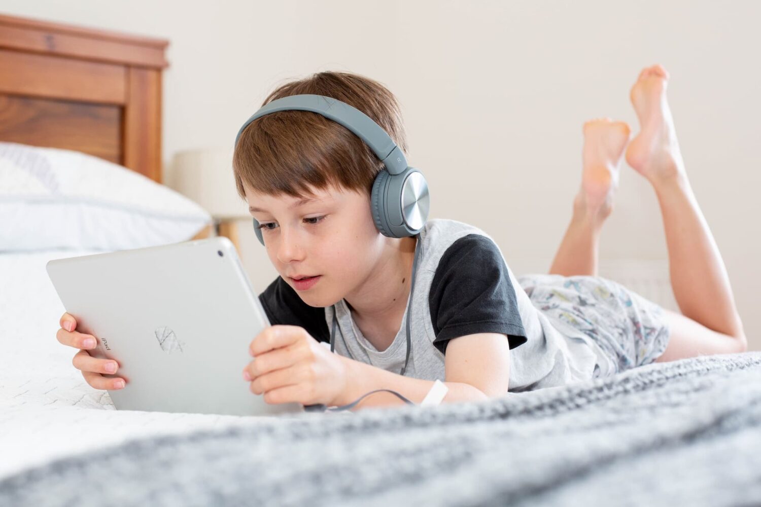 Child using old iPad with headphones on
