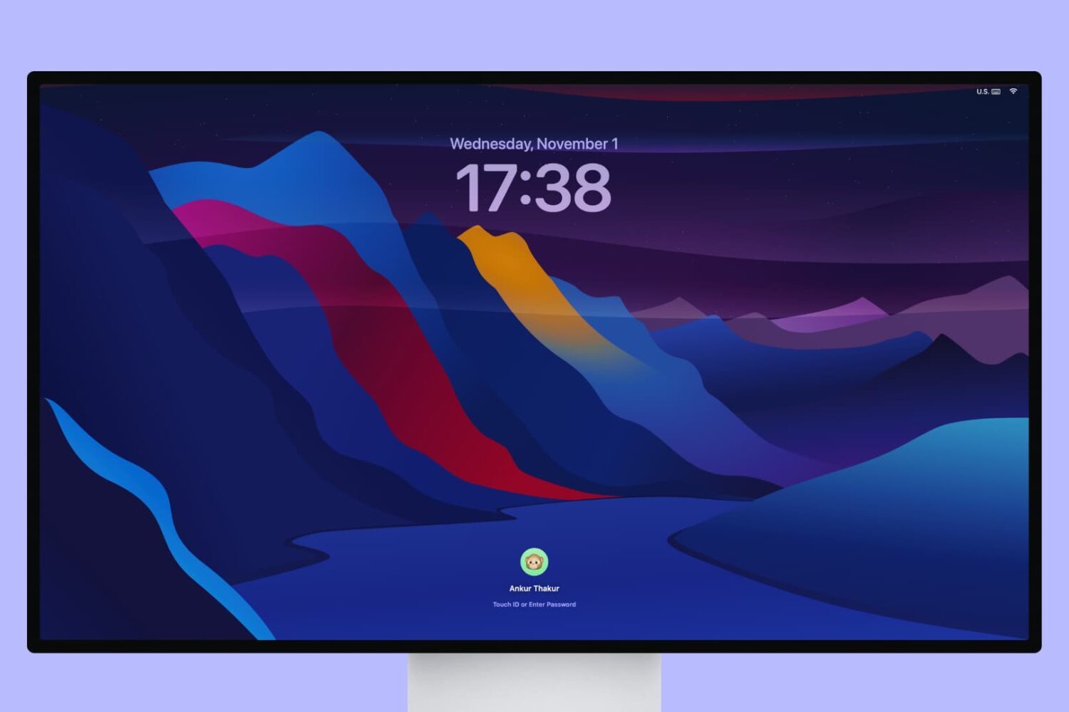 Apple Studio Display showing the macOS Lock Screen with a dark mountain wallpaper