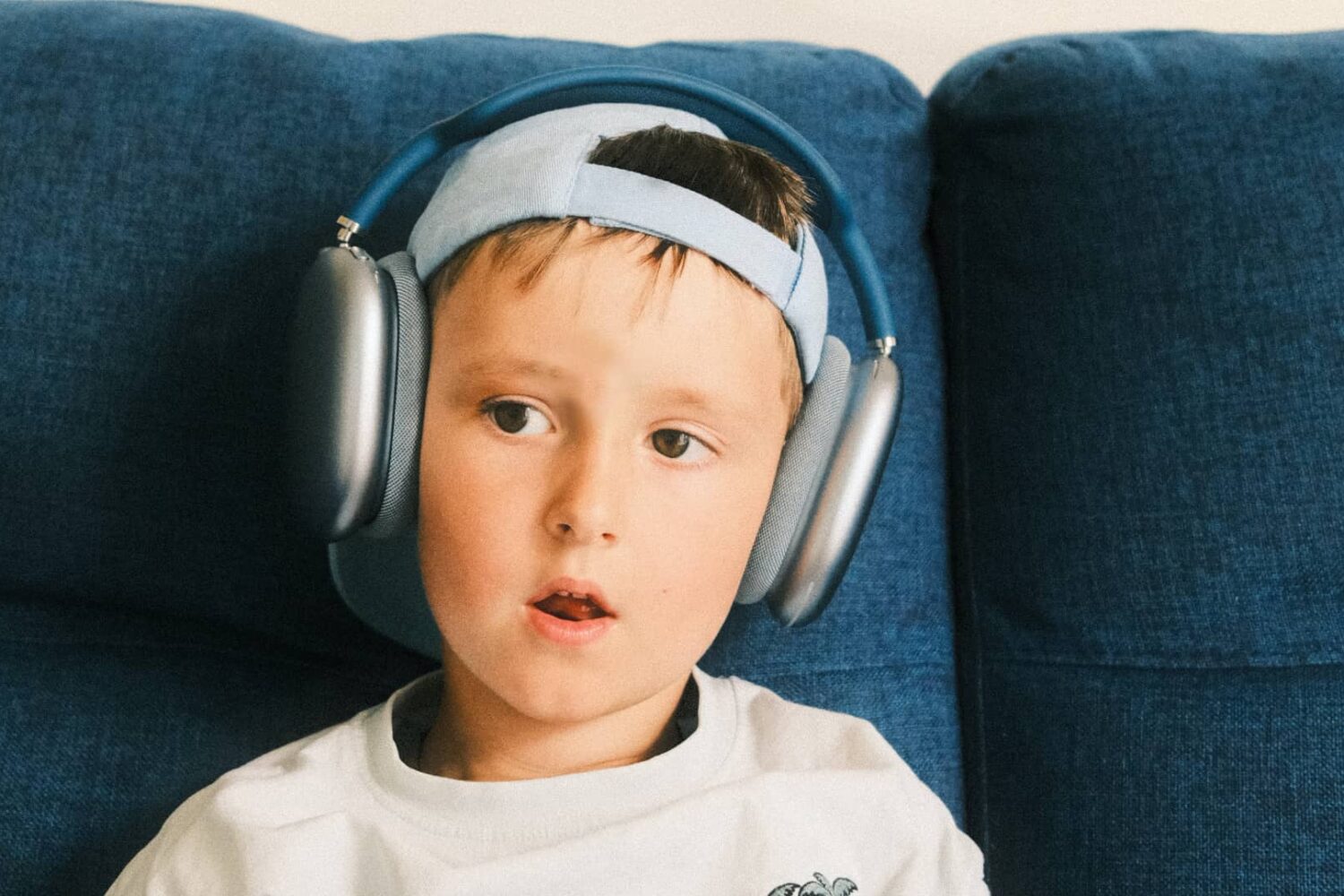 Little boy sitting on a couch, wearing AirPods Max headphones