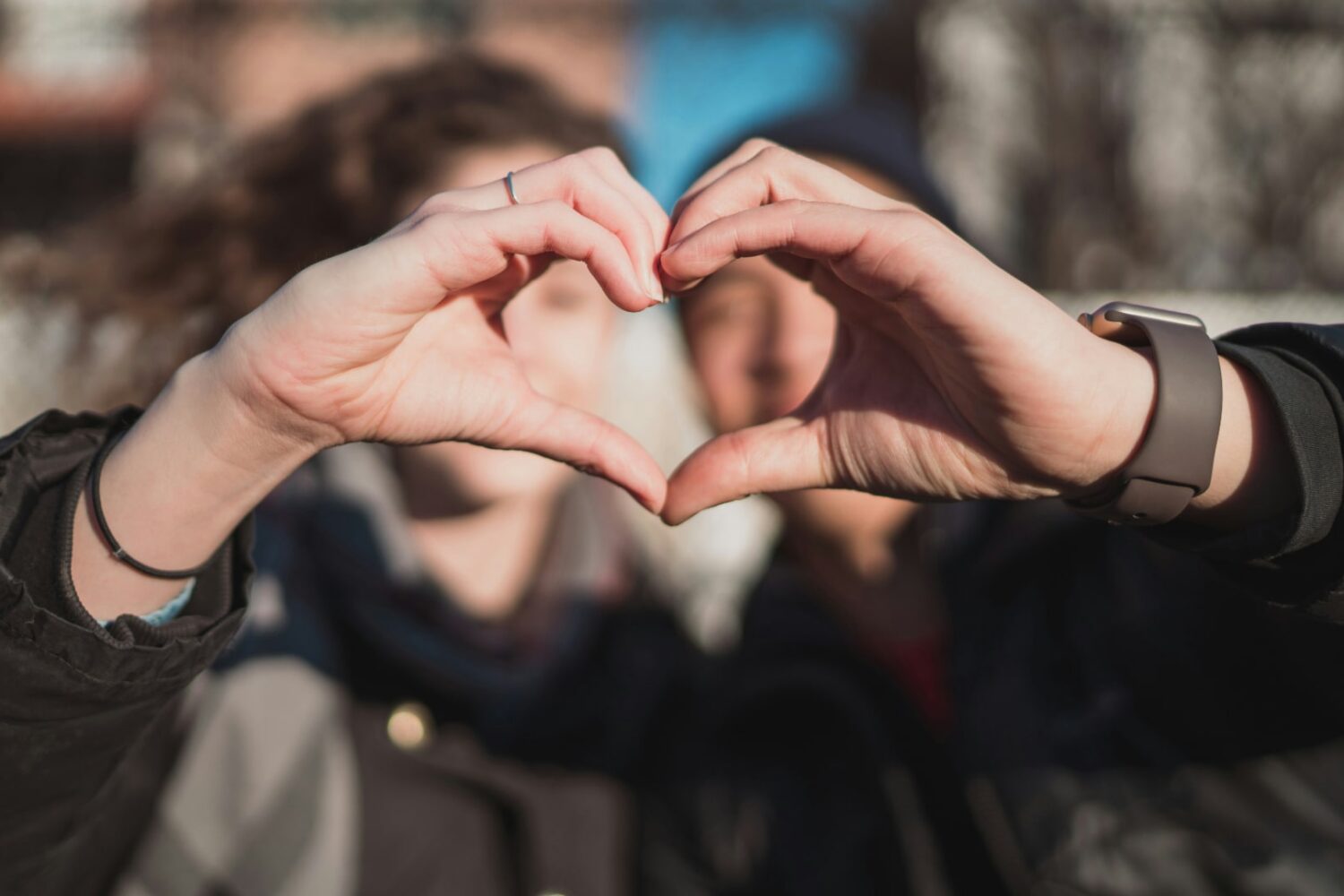 Man and woman combine hands to form a heart hand gesture