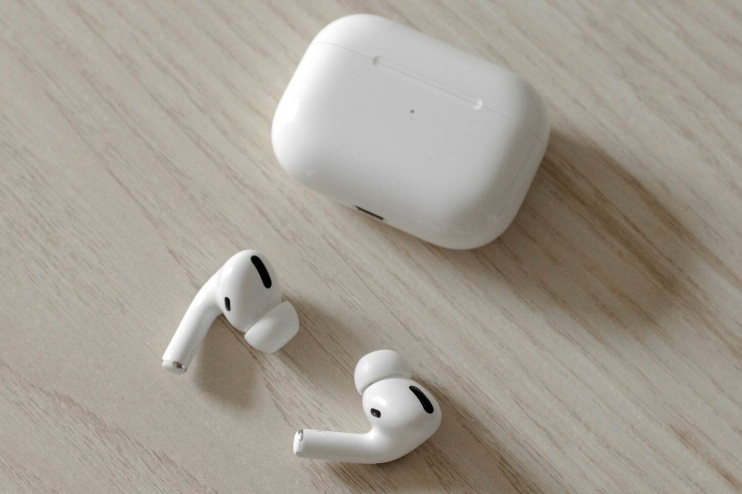 Apple's AirPods Pro earbuds on a wooden desk