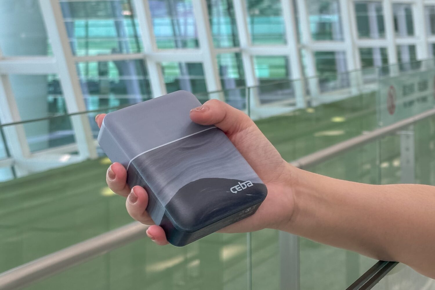 Person's hand holding Ceba RAPI power bank at the airport